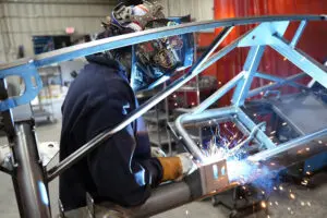 Technician welding an MK5 Roadster chassis frame
