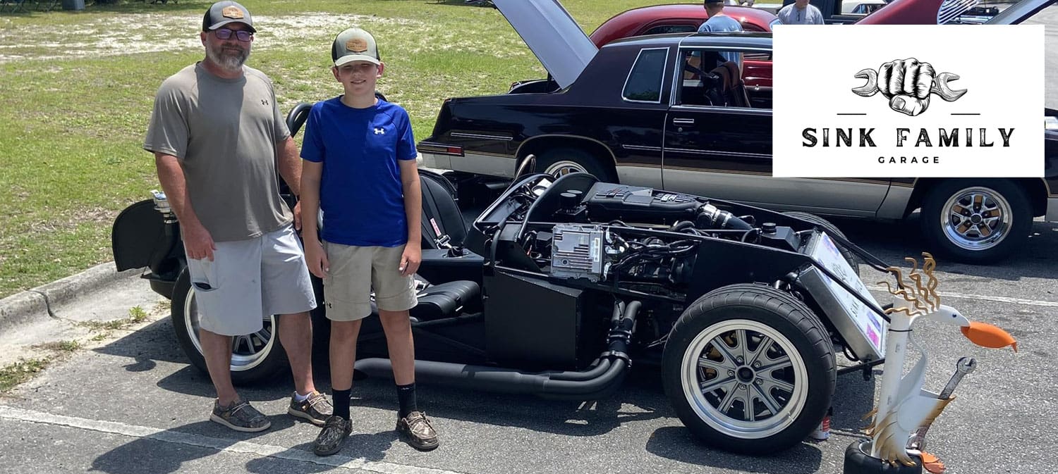 Boy and dad standing beside the bare chassis