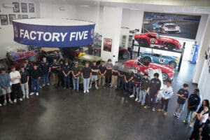 Group tour photo in front of Factory Five Racing signage