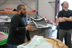 Technician demonstrating a fiberglass MK5 Roadster body panel